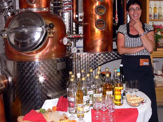 Frau Candinas mit der Destillieranlage und einer Auswahl ihrer Schnäpse